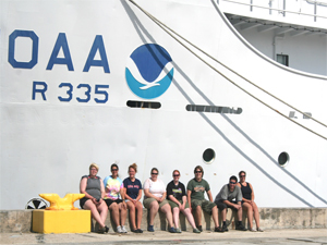 Marine biology students sitting on the dock in front of a NOAA research vessel