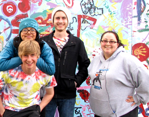 Students posing in front of mural.