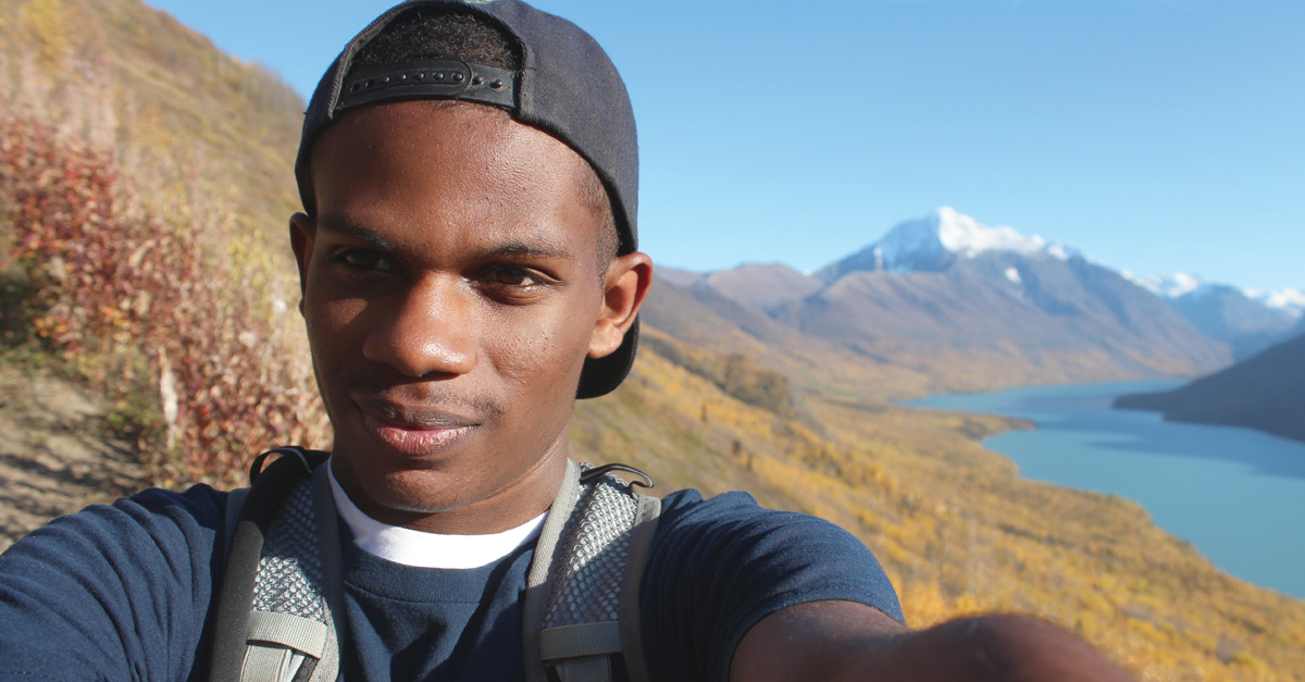 Raekwon Morgan with Alaskan mountain and lake view in the background.