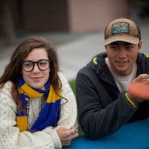 Male and Female Undergraduate students listening on a picnic table