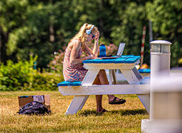 Student with laptop on picnic table