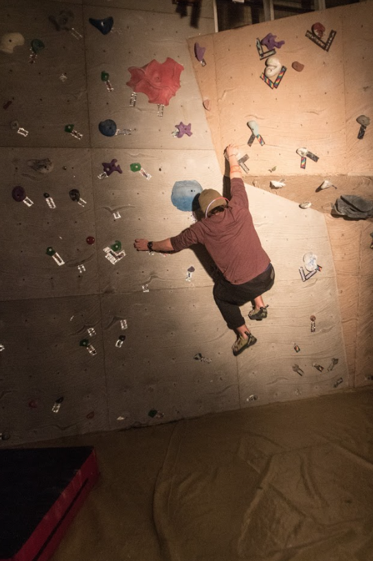 Climber following backlight reflective tape that marks the climbing wall holds