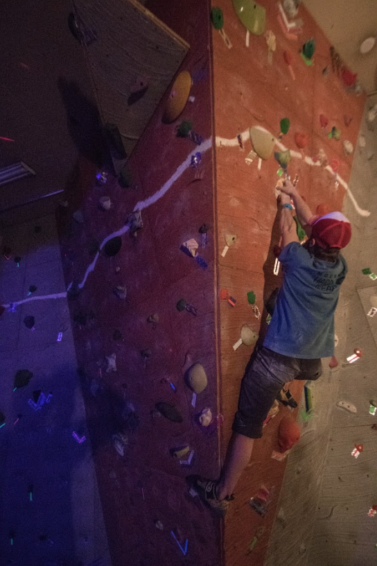 Climber following backlight reflective tape that marks the climbing wall holds