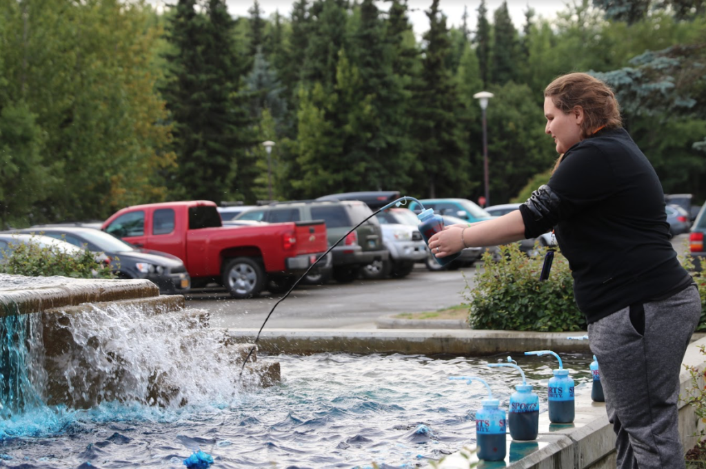Another student squirts the blue dye into the APU Atwood Building fountain.