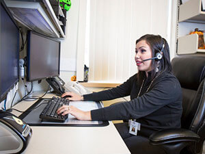 Woman looking at computer screen with headset on