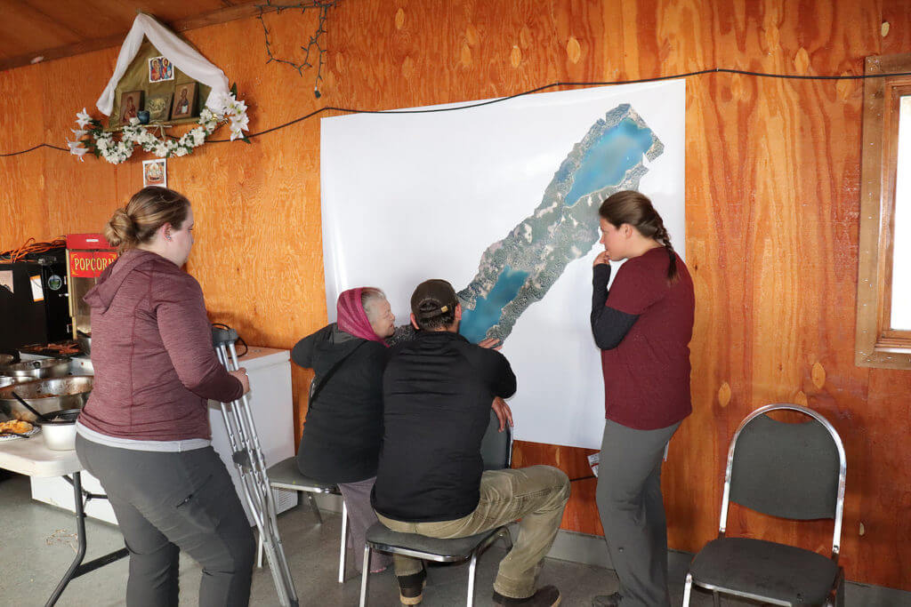 FAST Lab students discuss the mosaiced drone images of the Nanwalek lake system with community members.