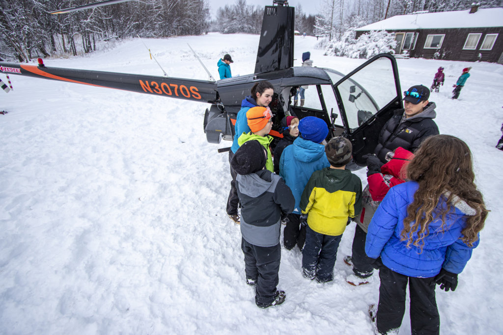 Kellogg Field School students gather around a helicopter as the pilot discusses how to fly the aircraft.
