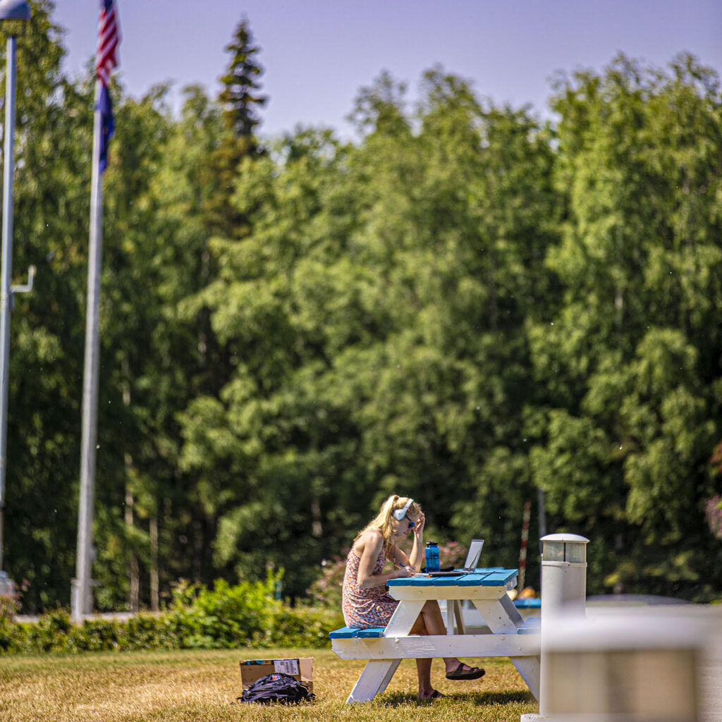 Student studies on the lawn outside of the Carr Gottstein building.