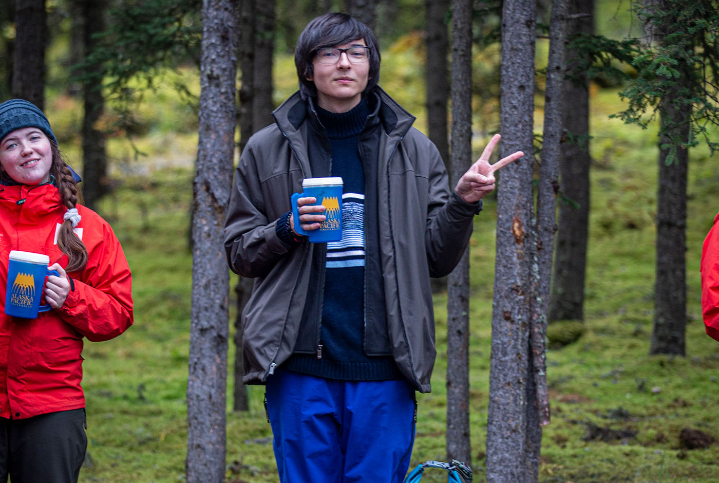 student holding a mug in the woods