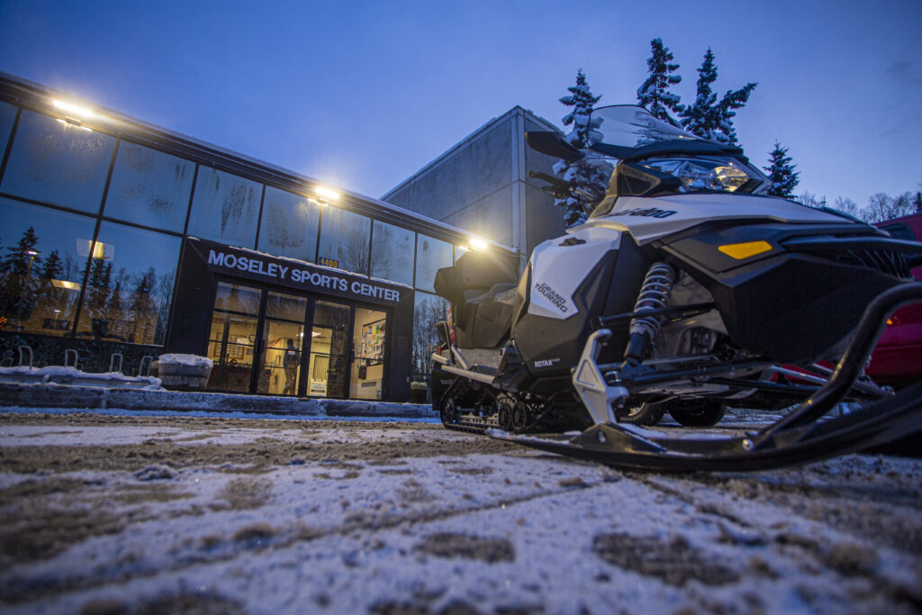 Snowmachines outside of Moseley Sports Center awaiting the ski trail grooming adventure on the campus of Alaska Pacific University.