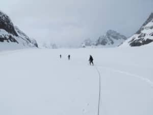 Three researchers tethered together walk across an ice field. Photo credit: Jason Geck
