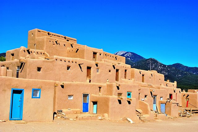 A three-story Taos Pueblo building under blue sky