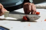 A close-up image of hands filleting salmon