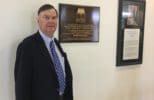 Rasmuson stands by a commemorative plaque in Rasmuson Hall