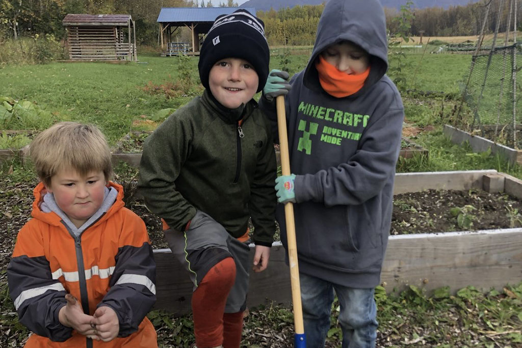 three kids working on vegetable garden