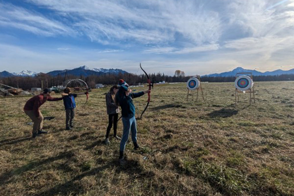 kids practicing bow and arrow shooting with targets