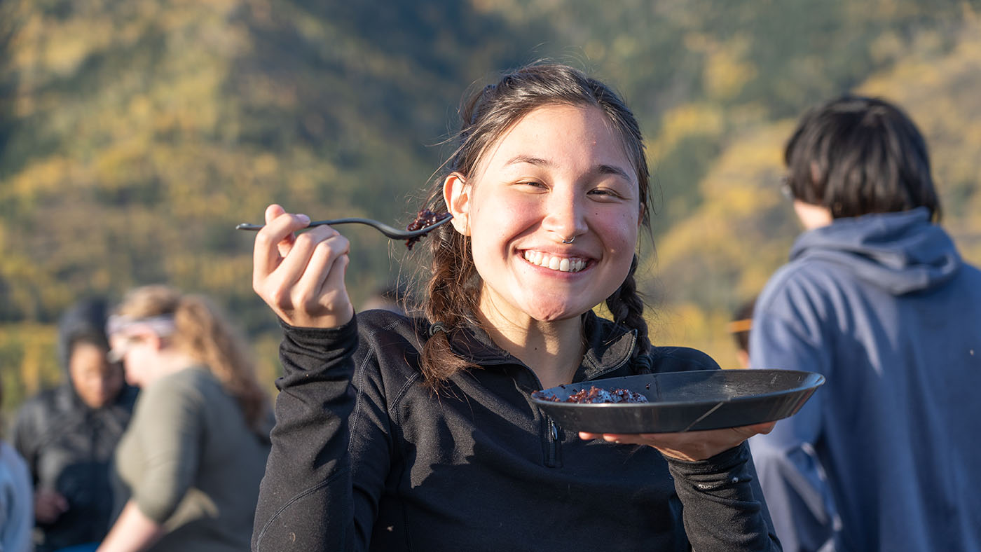 young woman holding a fork and smiling outdoors