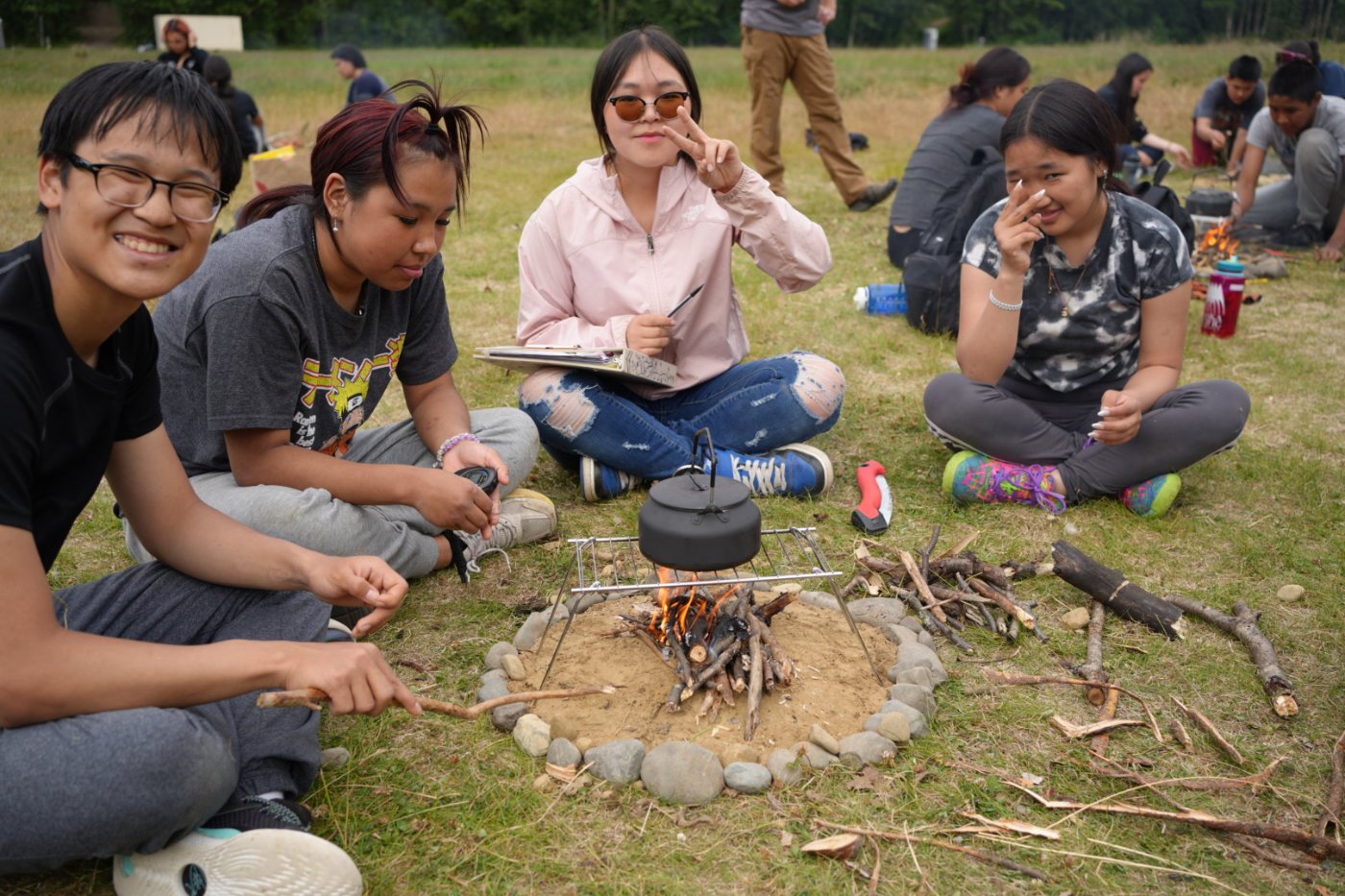Alaska Pacific University high school program students gathered around a campfire outdoors